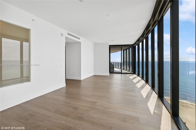 empty room with a water view, wood-type flooring, and expansive windows