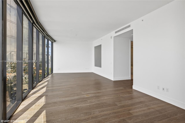 spare room featuring floor to ceiling windows and dark hardwood / wood-style floors