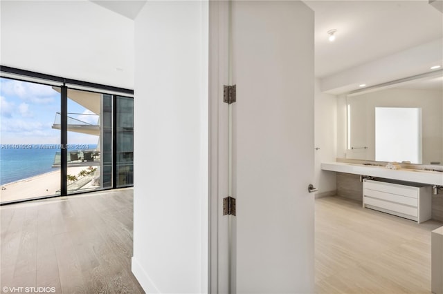 hallway featuring plenty of natural light, a water view, and light hardwood / wood-style flooring