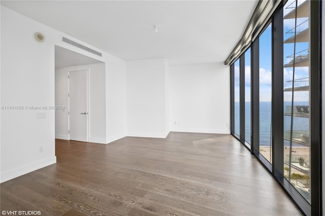 spare room with plenty of natural light, a wall of windows, dark hardwood / wood-style flooring, and a water view