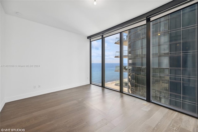 spare room with a water view, expansive windows, and light hardwood / wood-style flooring