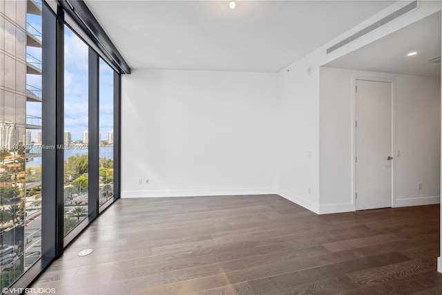 unfurnished room with plenty of natural light, floor to ceiling windows, and dark hardwood / wood-style flooring