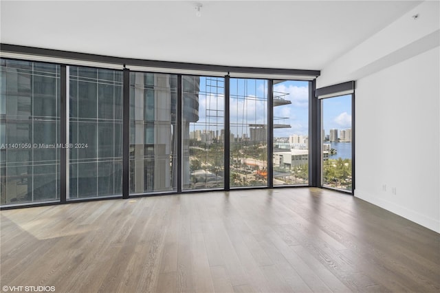 empty room with a wall of windows and hardwood / wood-style floors