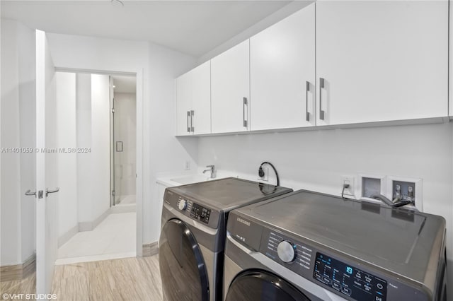 laundry room featuring washing machine and dryer, cabinets, light hardwood / wood-style floors, electric dryer hookup, and hookup for a washing machine