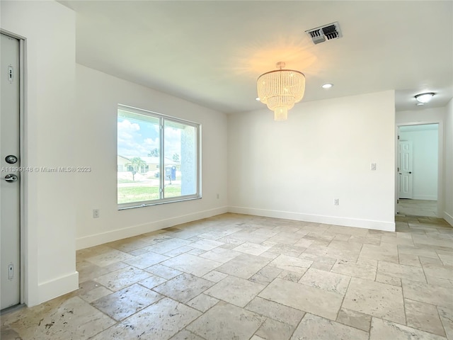 tiled spare room featuring a chandelier