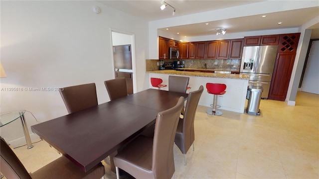 dining space with track lighting and light tile floors