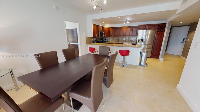 dining space with rail lighting and light tile floors