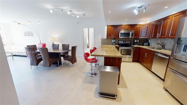 kitchen featuring stainless steel appliances, light tile flooring, sink, and light stone counters