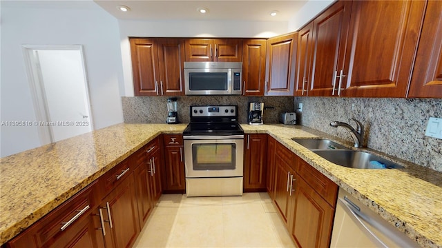 kitchen with backsplash, appliances with stainless steel finishes, and light stone countertops