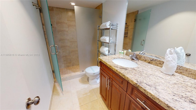 bathroom featuring toilet, tile flooring, an enclosed shower, and vanity