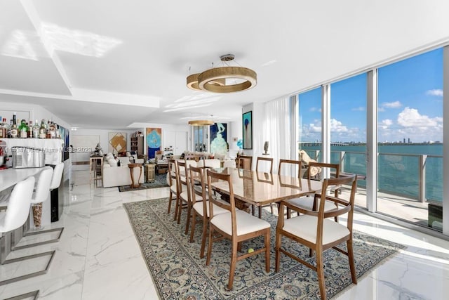 dining room with a water view, floor to ceiling windows, and light tile floors