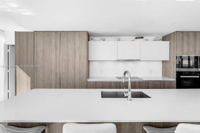 kitchen featuring white cabinets, a kitchen bar, and sink