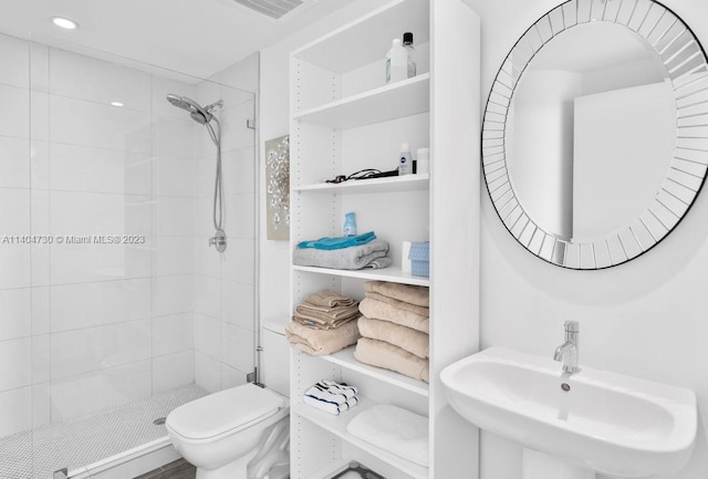 bathroom with sink, toilet, and tiled shower