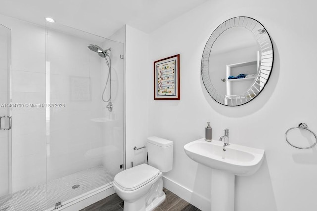 bathroom with toilet, a shower with door, and wood-type flooring