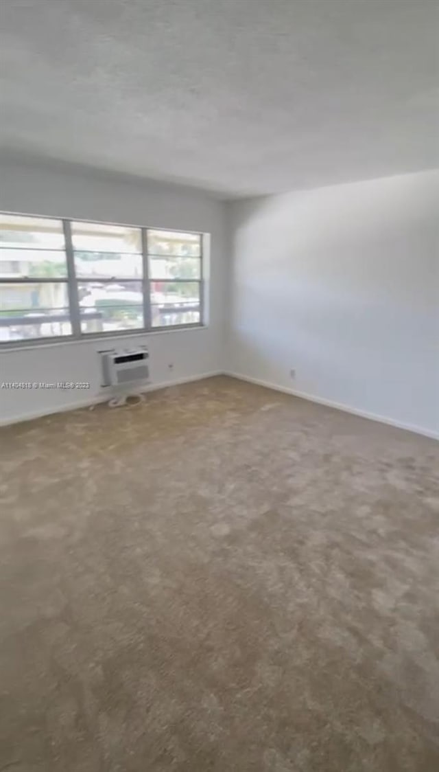 unfurnished room featuring carpet floors and a wall mounted air conditioner