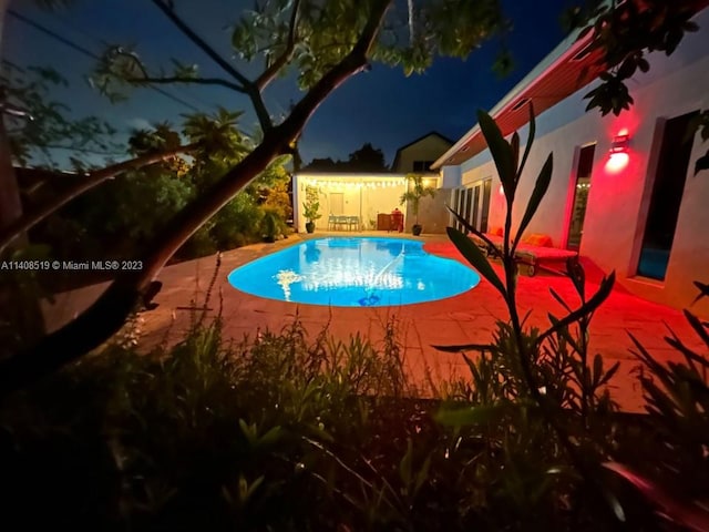 pool at night with a patio area