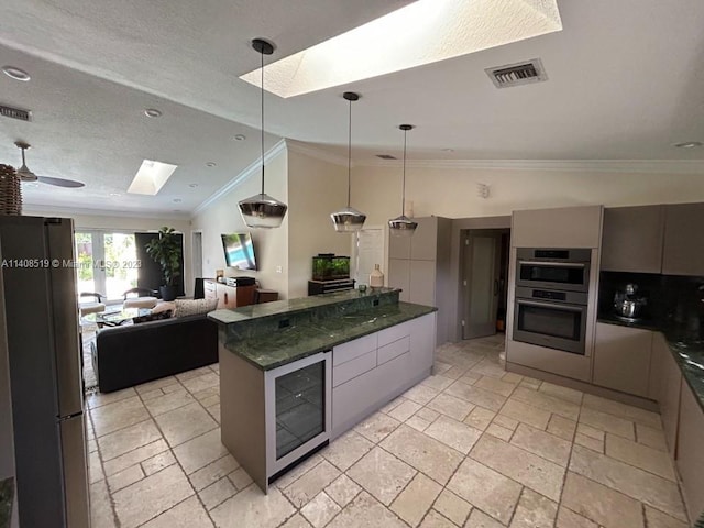 kitchen with ceiling fan, hanging light fixtures, ornamental molding, dark stone countertops, and stainless steel appliances