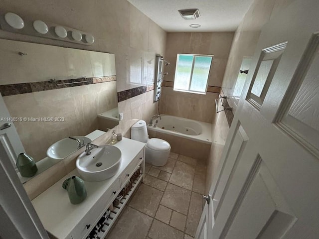 bathroom with toilet, vanity, a bath to relax in, tile walls, and tile flooring