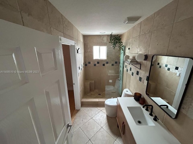 bathroom featuring tile walls, toilet, tiled shower, tile floors, and vanity