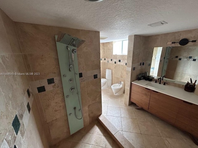 bathroom featuring tile walls, tile floors, a textured ceiling, toilet, and a bidet