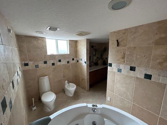 bathroom with a bidet, a textured ceiling, toilet, and tile walls