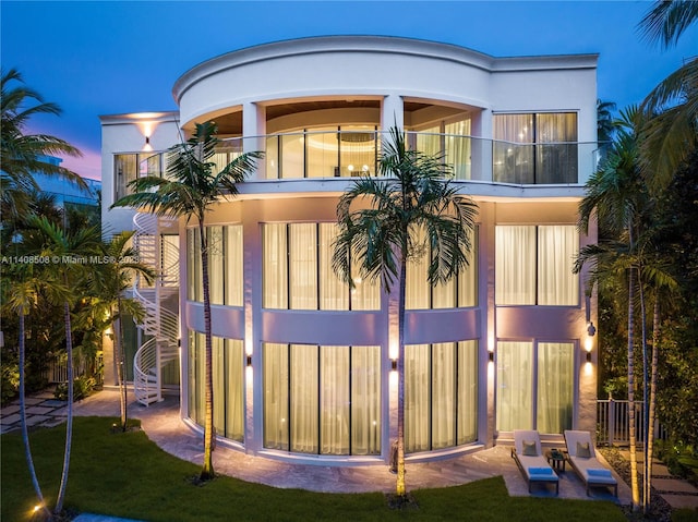 rear view of property featuring a balcony, a patio area, and a yard