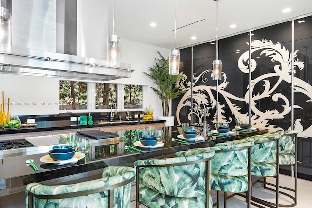 kitchen featuring ventilation hood, decorative light fixtures, a breakfast bar, and sink