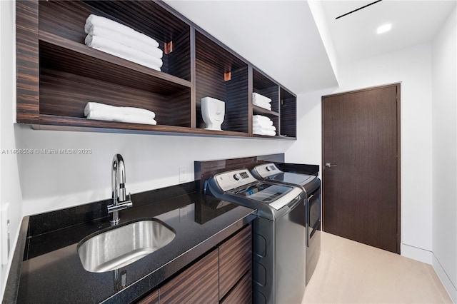 laundry room featuring washing machine and clothes dryer, cabinets, and sink