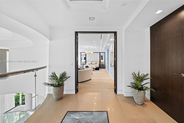 hallway featuring a notable chandelier and light wood-type flooring