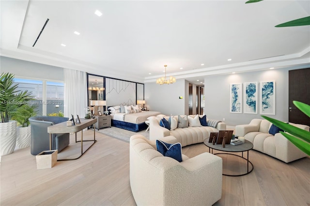 living room with a raised ceiling, a notable chandelier, and light hardwood / wood-style flooring