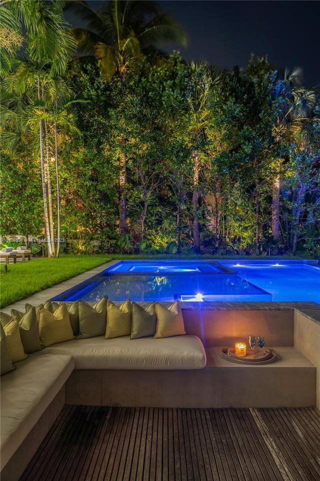 pool at night featuring an outdoor living space