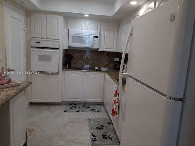 kitchen with white appliances, light tile floors, white cabinets, dark stone countertops, and tasteful backsplash