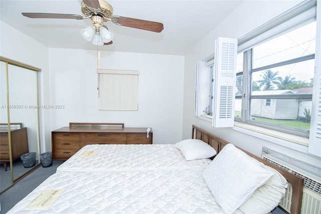 carpeted bedroom with ceiling fan, a closet, multiple windows, and radiator