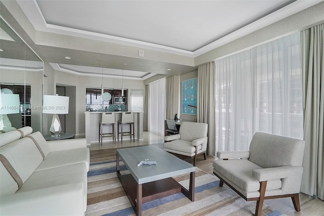 living room featuring a tray ceiling and light hardwood / wood-style flooring