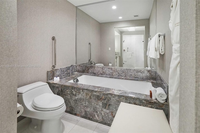 bathroom with toilet, tile floors, and a relaxing tiled bath