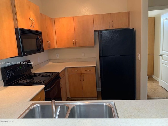 kitchen with black appliances, sink, and light tile flooring