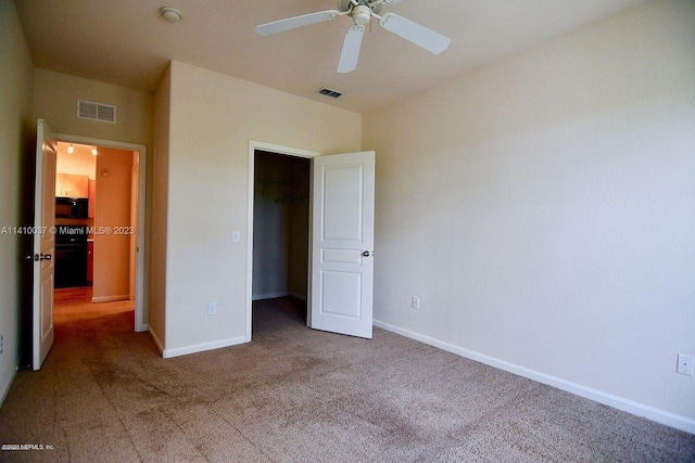 unfurnished bedroom featuring a closet, dark colored carpet, and ceiling fan