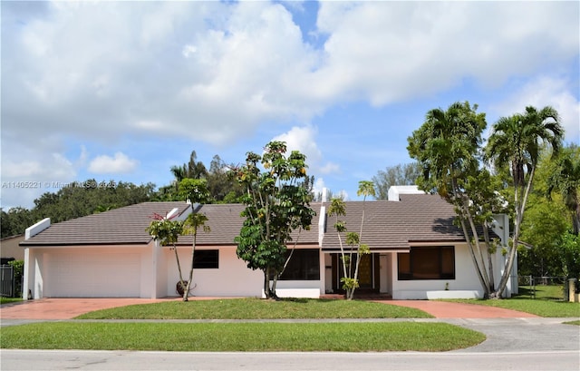 ranch-style house featuring a garage and a front lawn