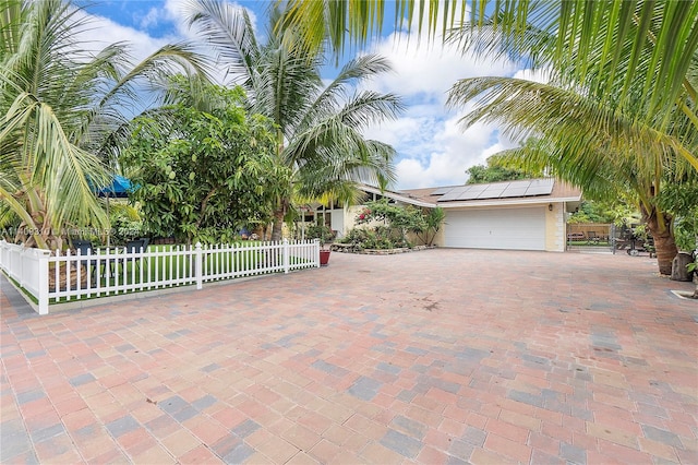 371 Bishop Dr, Delray Beach, FL 33445 - view of front of house featuring a garage, fence private yard, roof mounted solar panels, and decorative driveway