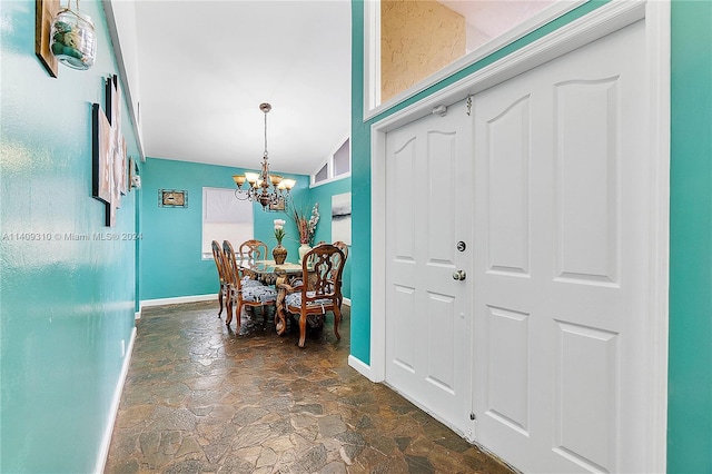 dining area featuring a chandelier, stone finish floor, and baseboards