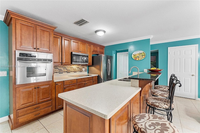 kitchen featuring stainless steel appliances, sink, decorative backsplash, an island with sink, and ornamental molding