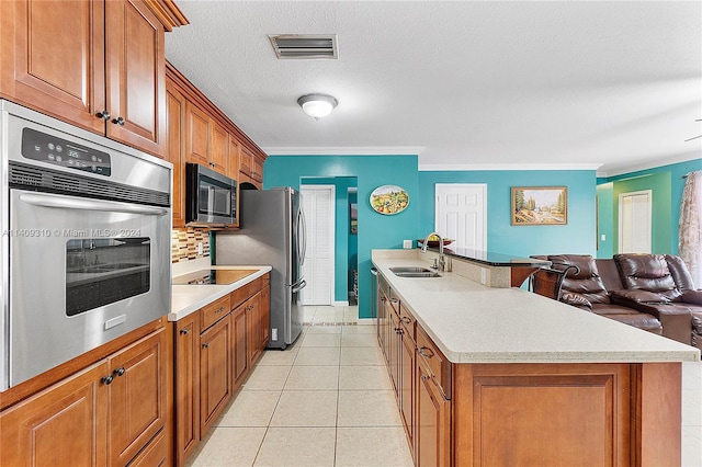 kitchen featuring a center island with sink, visible vents, appliances with stainless steel finishes, brown cabinets, and a sink