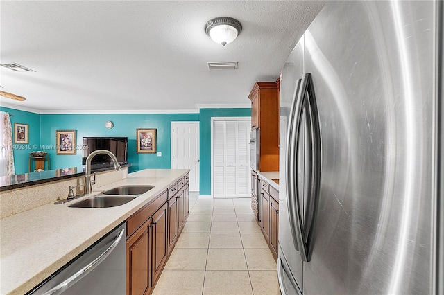 kitchen with light tile patterned floors, a textured ceiling, stainless steel appliances, sink, and ornamental molding