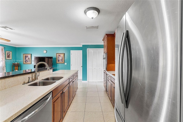 kitchen with appliances with stainless steel finishes, brown cabinetry, light countertops, and a sink