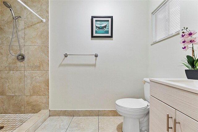 bathroom featuring tile patterned floors, vanity, a tile shower, and toilet