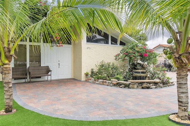 entrance to property featuring a patio area and stucco siding