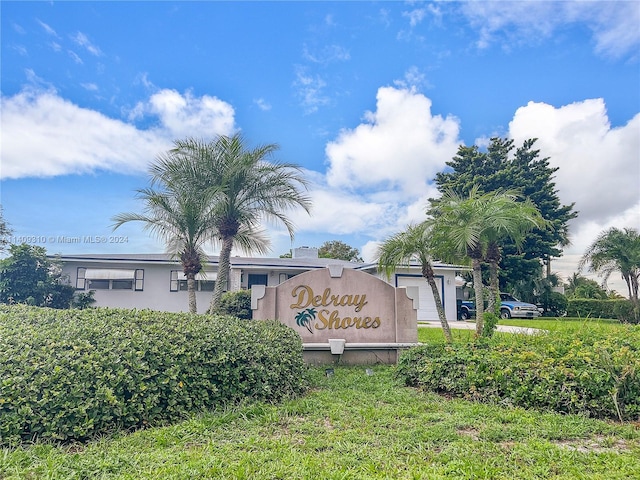 community sign featuring driveway and an attached garage