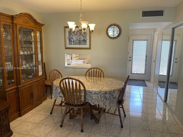 dining space with light tile floors, a textured ceiling, and an inviting chandelier