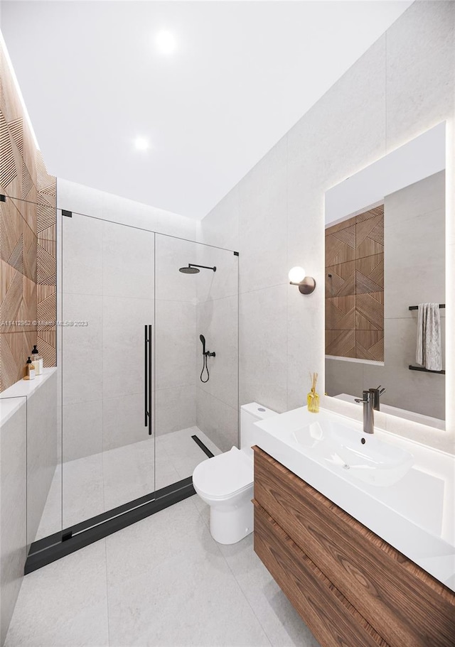 bathroom with tile walls, toilet, a shower with door, tile floors, and large vanity