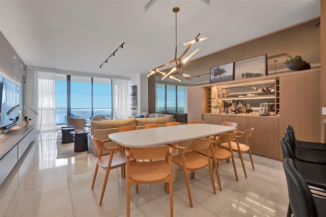 tiled dining area with a healthy amount of sunlight, track lighting, and a notable chandelier